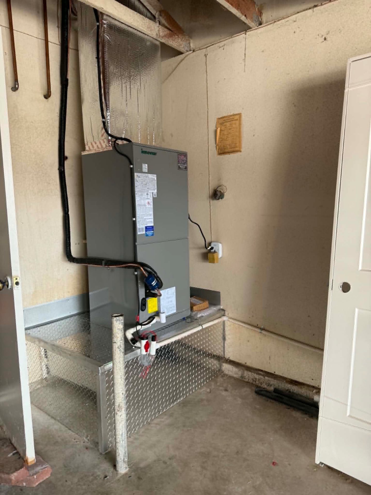 Innovair residential air handler installed on a raised platform inside a garage utility area