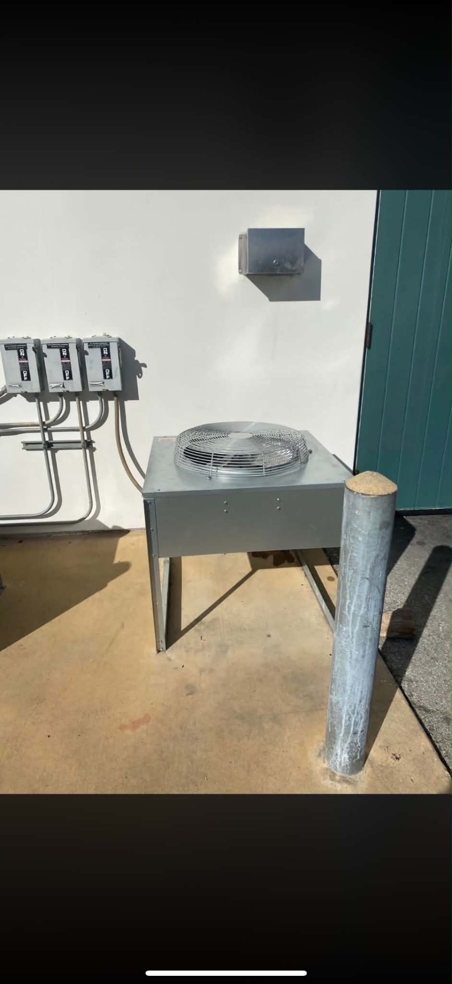 Outdoor commercial refrigeration condensing unit with electrical disconnects installed against a white wall